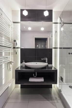 A modern bathroom with a large mirror, a white sink, and a glass shower enclosure. - Pałac Brzezno (Prusice)