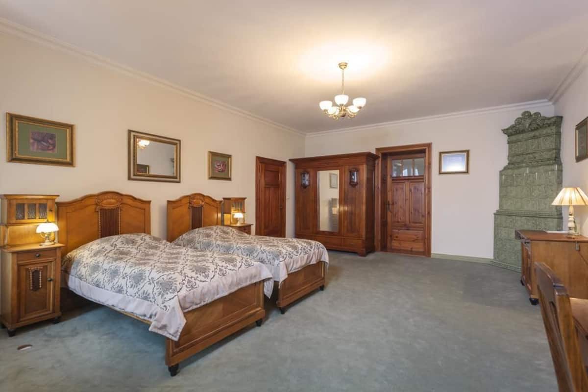 A bedroom with two wooden beds, a chandelier, and wooden furniture.