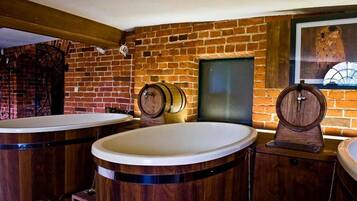 A bathroom with wooden barrels as sinks, a brick wall, and a framed picture on the wall.