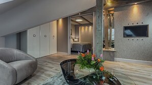 Una sala de estar moderna con un sofá, una mesa de centro de vidrio con flores y un televisor montado en una pared con textura.