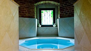 Un jacuzzi con vista a un muro de ladrillo y una ventana que da a la vegetación.