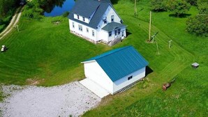 Een groot huis met een blauw dak, omgeven door een verzorgd gazon en een klein vijvertje.