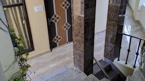 A staircase with marble steps and a handrail, leading to a door with a geometric pattern.
