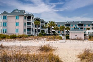 A beachfront hotel with multiple balconies, a sandy beach in the foreground, and a clear sky. - See, Feel & Hear the Ocean from this Light-Filled Condo w/ Community Pool & Private Screened Porch. (Isle of Palms)