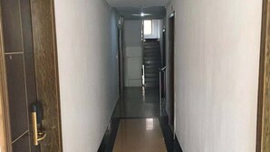 A long, narrow hallway with a black and beige floor, a fire extinguisher on the right, and a door on the left. - ruixing hotel (Yangjiang)