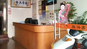 A reception desk with a wooden counter, a mounted television, and a framed artwork on the wall. - ruixing hotel (Yangjiang)