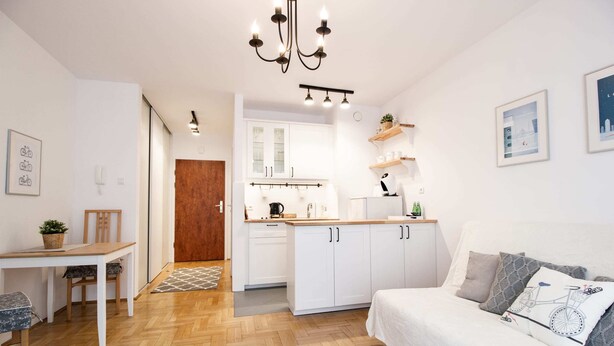A modern, well-lit apartment with a kitchenette, dining area, and a cozy living space with a sofa and cushions. - Arkadia Chillout Apartment (Warsaw)