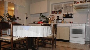 Een keuken met witte kastjes, een fornuis en diverse keukengerei.