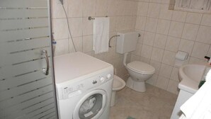 Een kleine badkamer met een wasmachine, toilet en wastafel.
