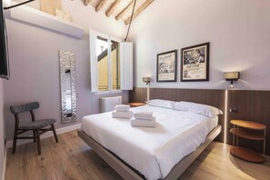 A modern hotel room with a large bed, a chair, a mirror, and artwork on the wall. - Giglio di Firenze by Mmega (Florence)