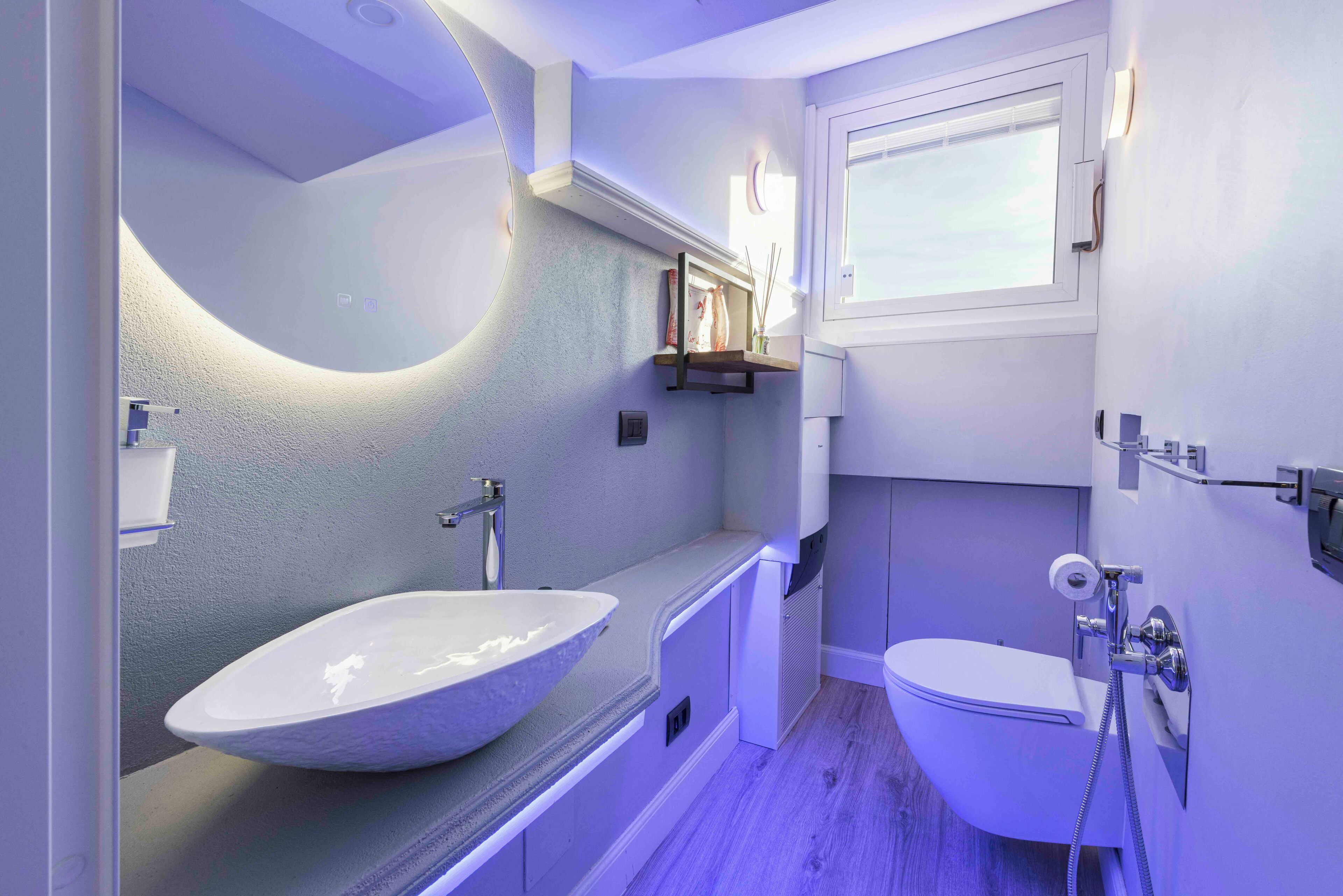 A modern bathroom with a large vessel sink, a toilet, and a shower.