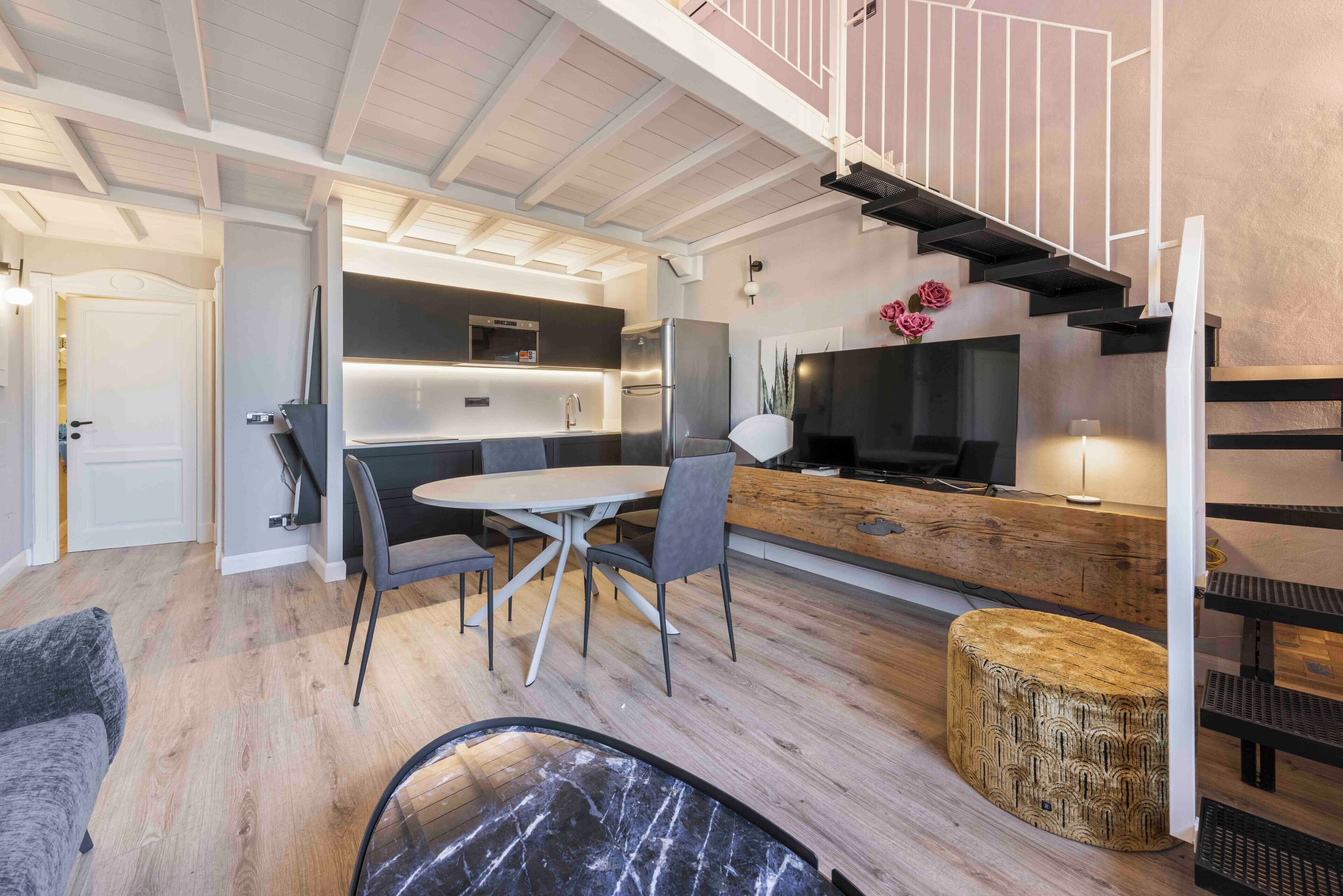 Una cocina moderna con comedor, una escalera y una sala de estar con sofá y mesa de centro.