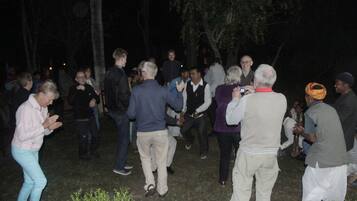 Un grupo de personas reunidas al aire libre de noche, posiblemente en un evento social.