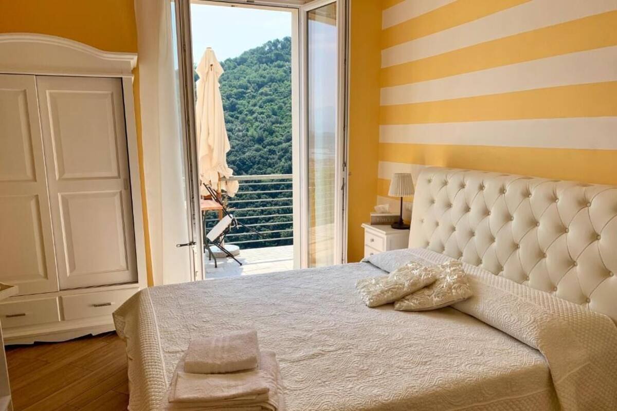 Ein Schlafzimmer mit Bett, Nachttisch, Kleiderschrank und einem Balkon mit Blick ins Grüne.