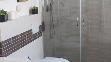Ein modernes Badezimmer mit einer Duschkabine, einer Toilette und einem Bidet.