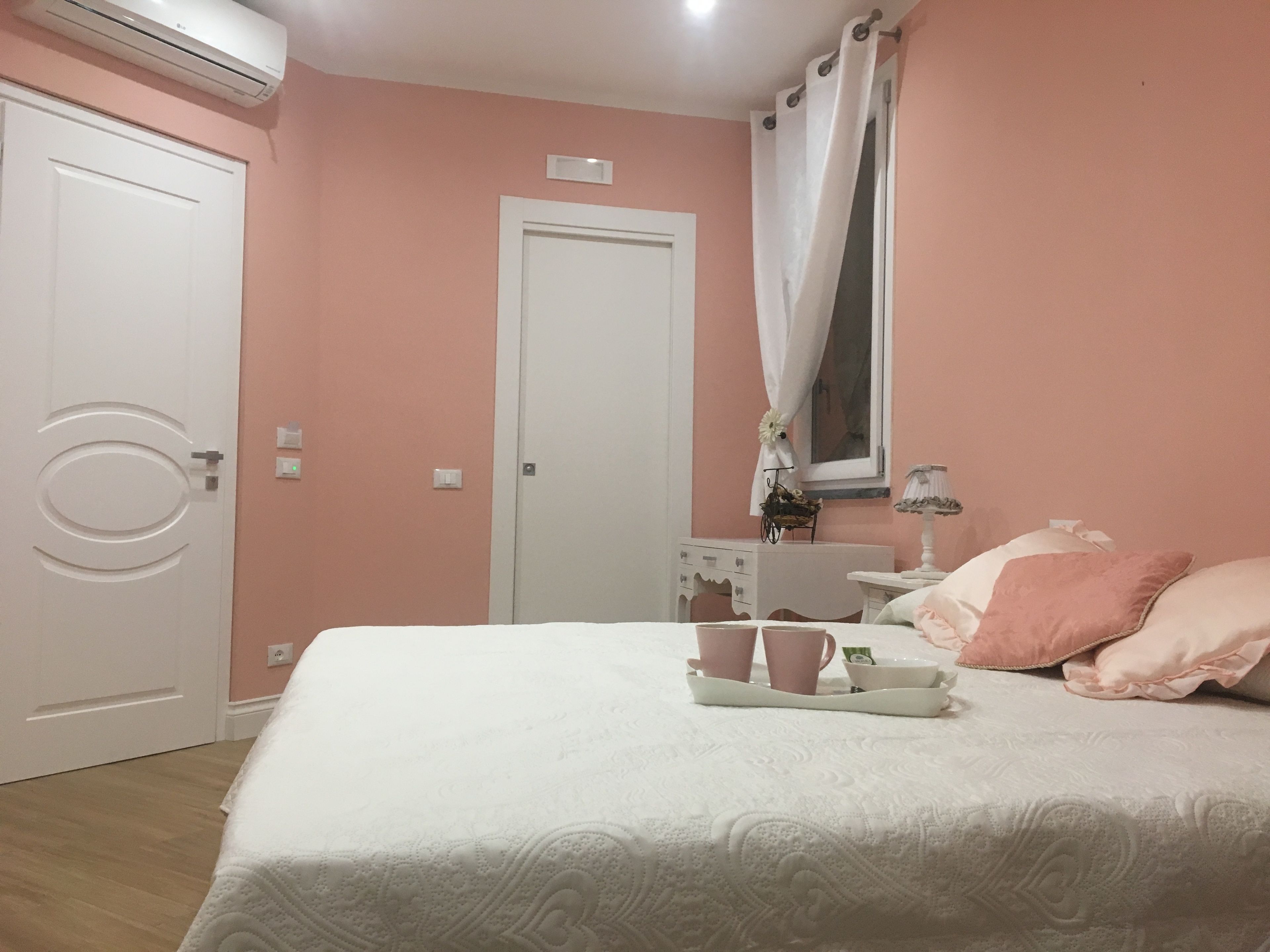 A bedroom with a bed, a bedside table, a lamp, and a window with curtains.
