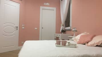 A bedroom with a bed, a bedside table, a lamp, and a window with curtains.