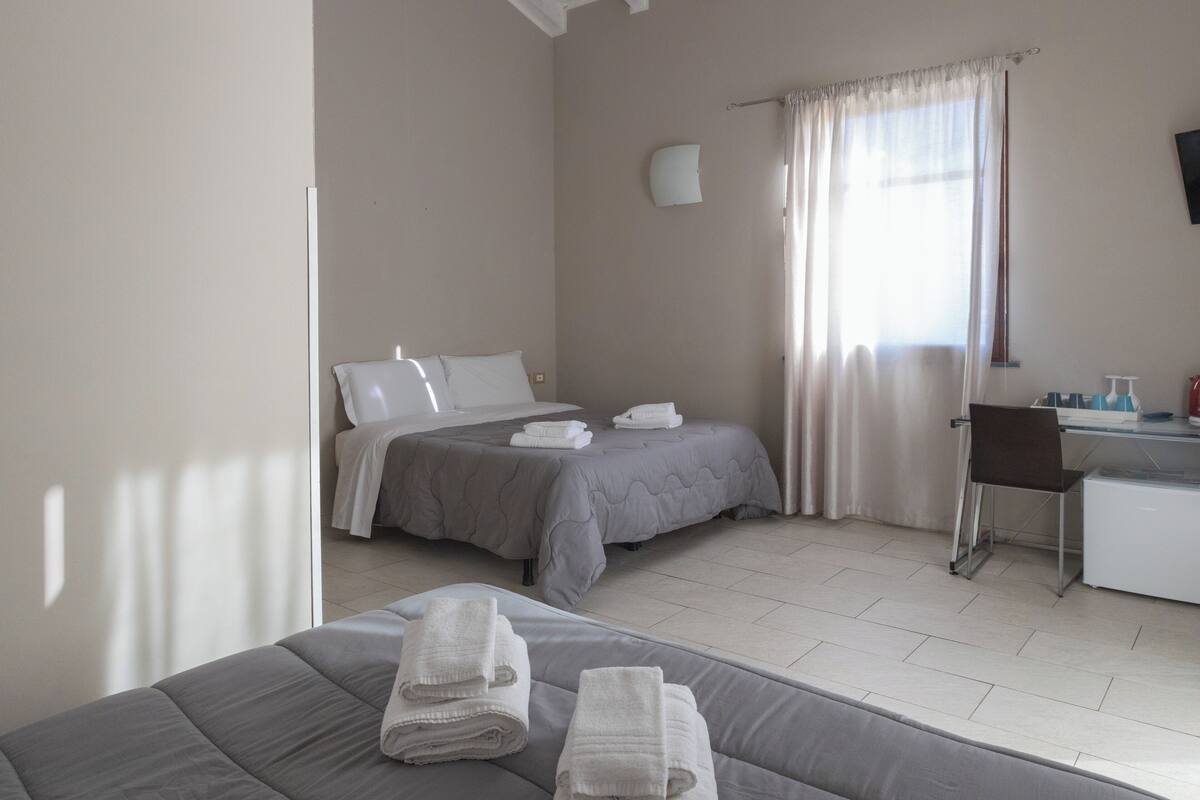 Ein Hotelzimmer mit zwei Betten, einem Schreibtisch und einem Sessel.