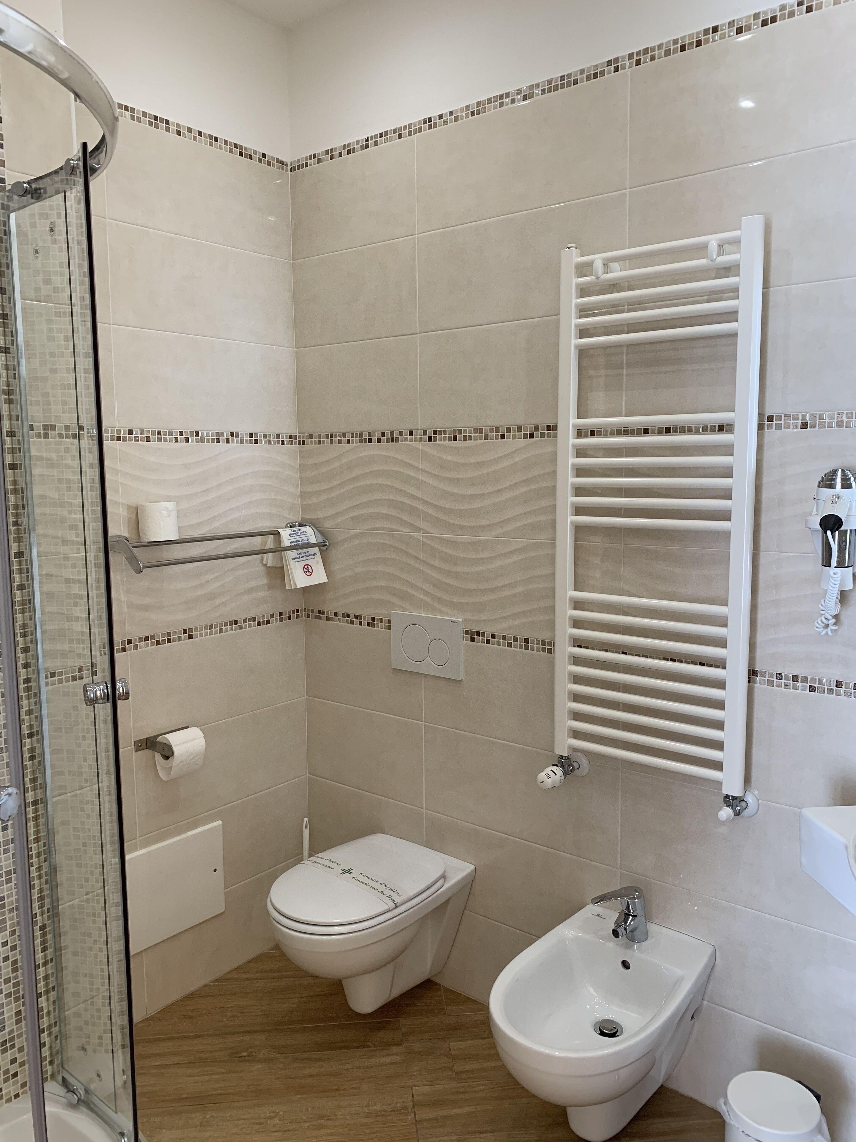 A modern bathroom with a glass shower enclosure, a toilet, bidet, and a sink.