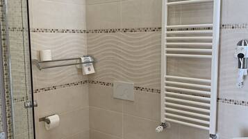 A modern bathroom with a glass shower enclosure, a toilet, bidet, and a sink.