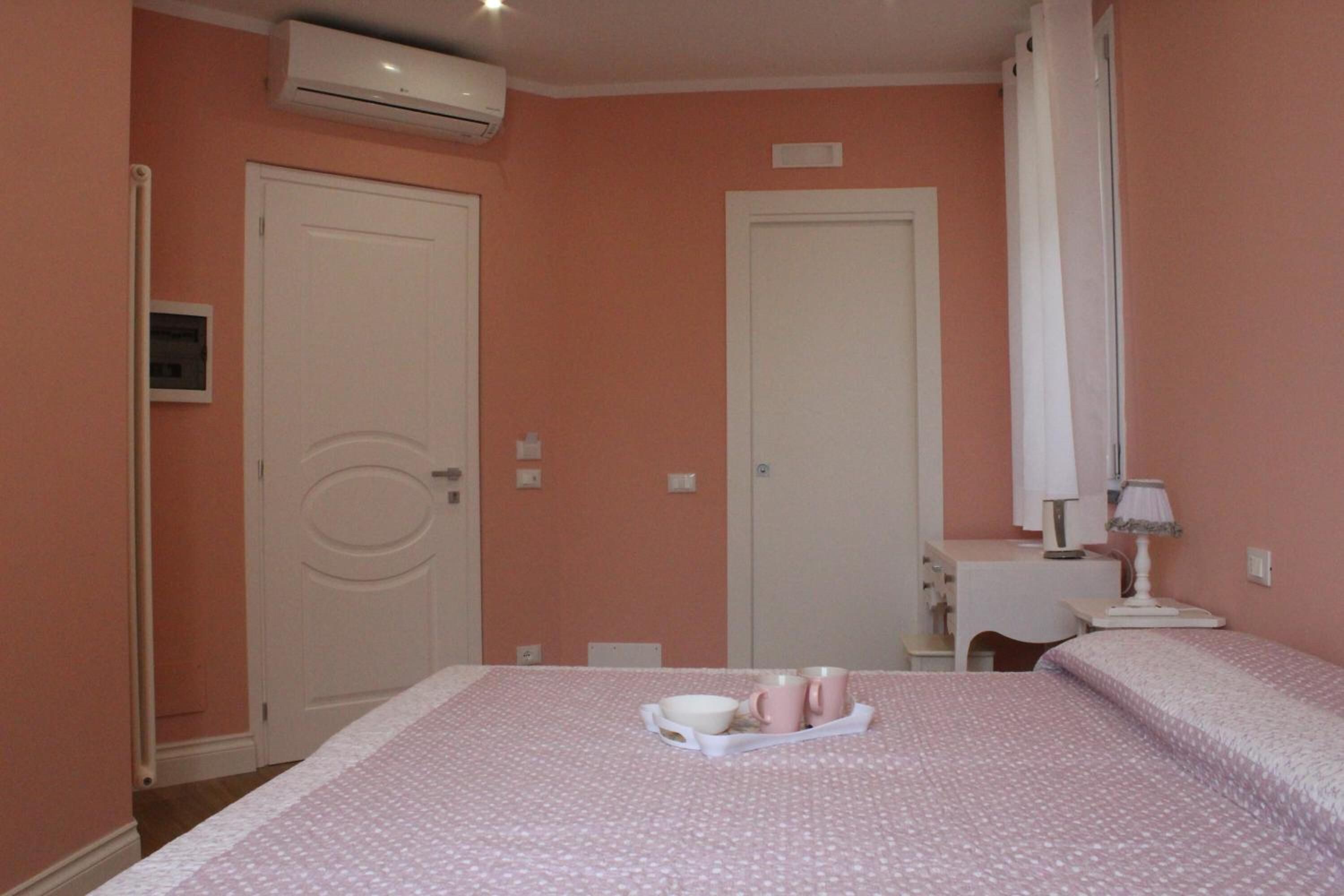 A bedroom with a bed, a desk, and an air conditioner.