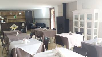 Zona pranzo con tavoli apparecchiati, un camino e un armadio con vetrate.