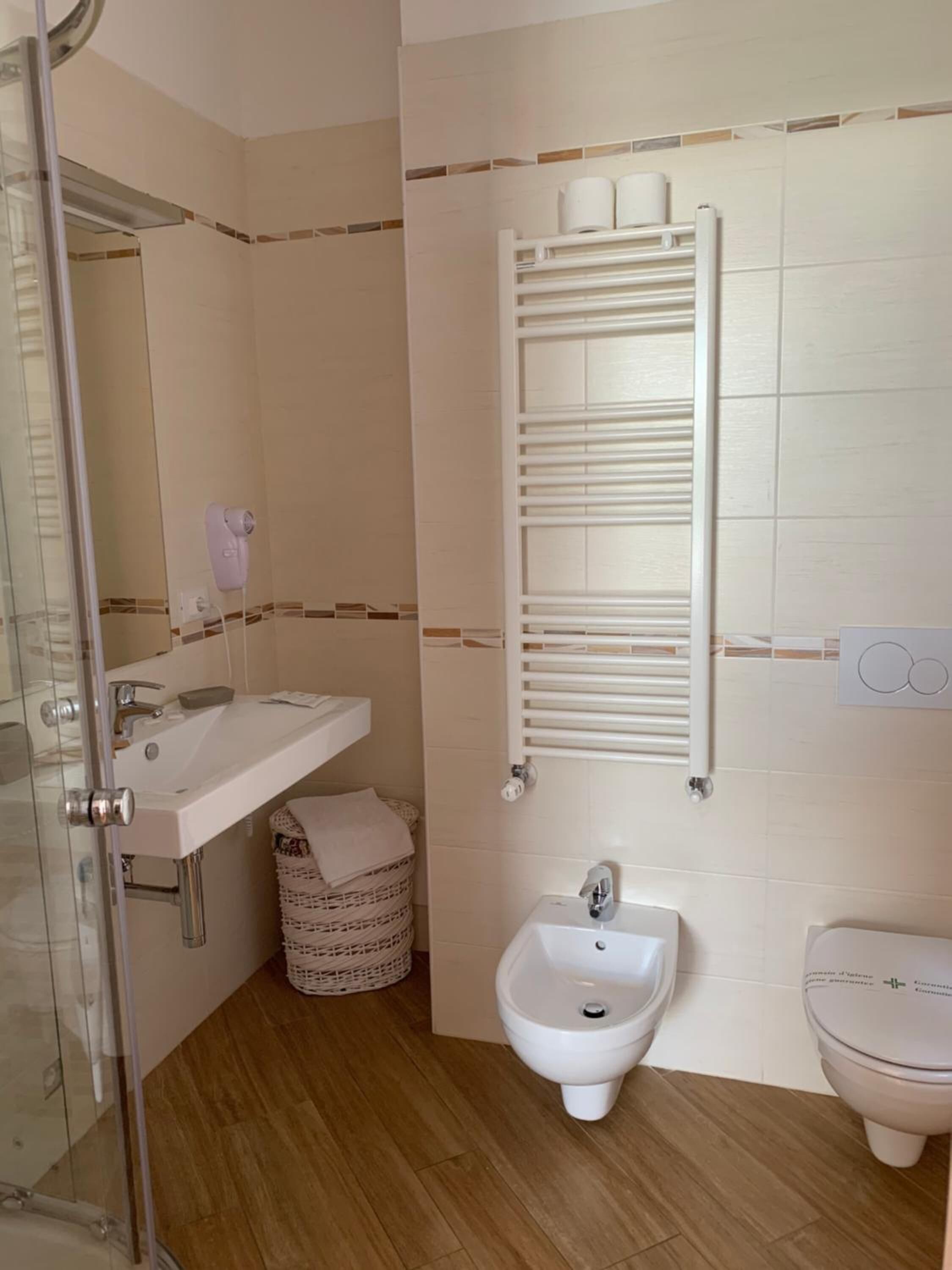Un baño con cabina de ducha de vidrio, un lavamanos blanco, un bidé y un inodoro.