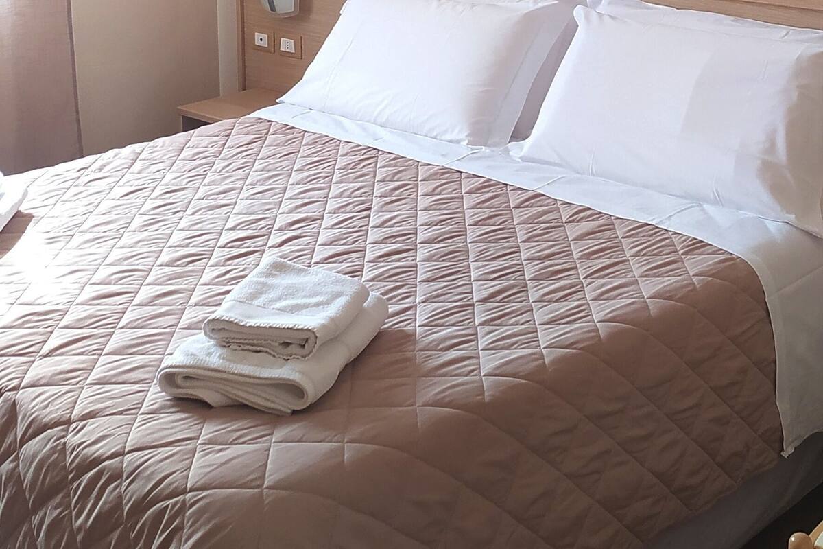 Ein Hotelzimmer mit Bett, Nachttisch, Spiegel und einer Wand mit horizontalen Streifen.