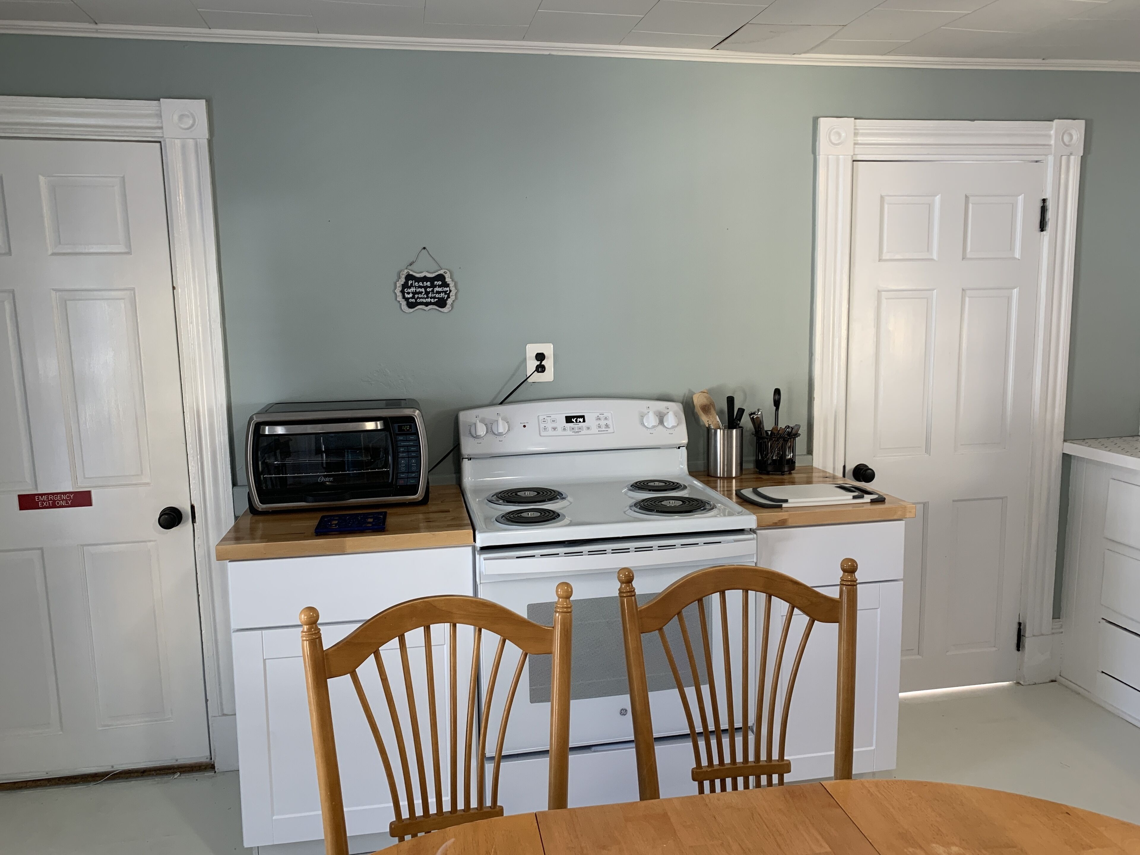 Cocina compacta con estufa blanca, horno tostador y sillas de madera.