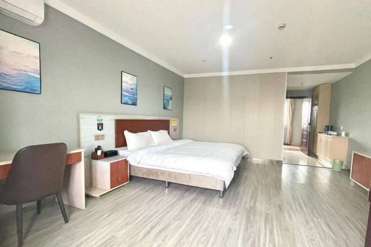 A hotel room with a bed, a desk, a chair, and a wardrobe.