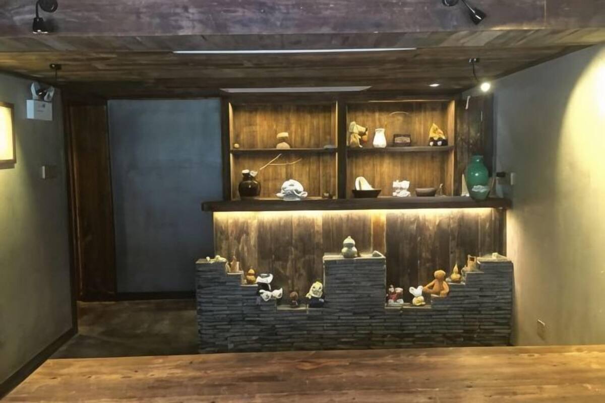 A room with a wooden reception desk, shelves with decorative items, and a stone wall display.