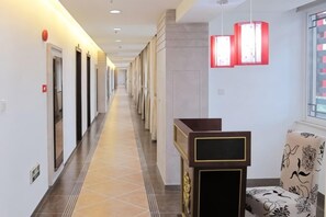 Un pasillo de hotel con puertas, una recepción y una silla.