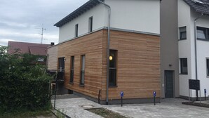 A modern building with a wooden facade, a flat roof, and a visible entrance. - High quality 1 1/2 room apt. with lake view and large terrace! (Allensbach)