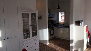 A kitchen with a wooden floor, white cabinets, and a window with a view of the outside. - High quality 1 1/2 room apt. with lake view and large terrace! (Allensbach)