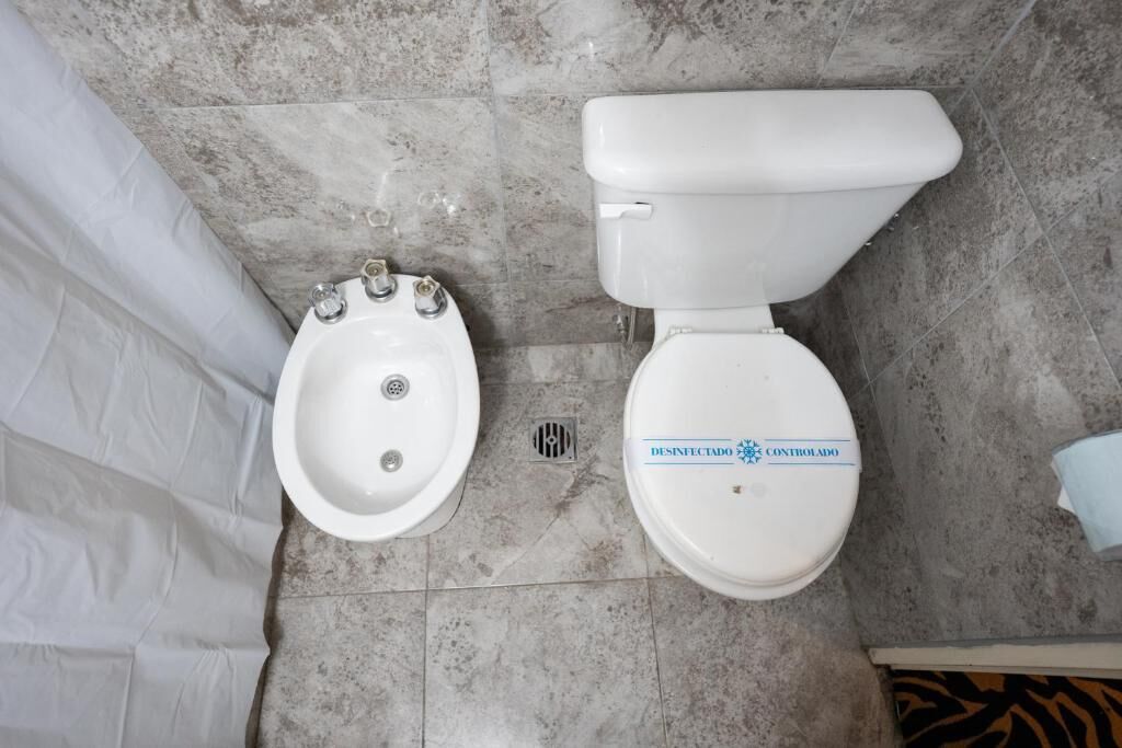A bathroom with a bidet, a toilet, and a shower curtain.
