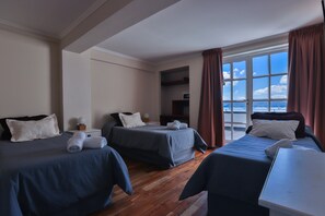 Ein Hotelzimmer mit zwei Betten, einem Schreibtisch und Meerblick.
