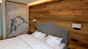 Ein Schlafzimmer mit Holzwandverkleidung, einem Bett mit weißer Bettwäsche und einem Bild von Skifahrern an der Wand.