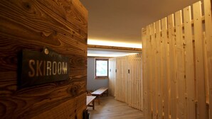 Ein Gang mit Holzwänden, einer Bank und einem Schild mit der Aufschrift 'SKIROOM'.