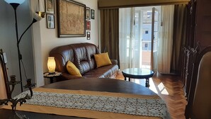 Une chambre d’hôtel avec un grand lit, un canapé en cuir, une petite table et une vue sur l’extérieur.