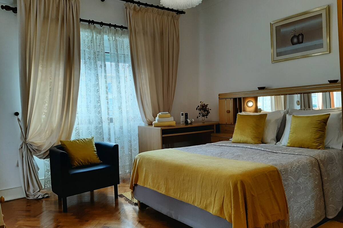 Een slaapkamer met een bed, een bureau, een stoel en een nachtkastje.