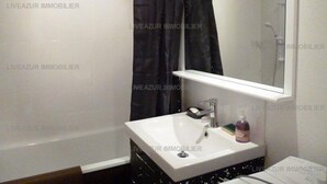 A bathroom with a white sink, a mirror, and a dark curtain. - Studio with terrace in residence with swimming pool for 4 (SANARY SUR MER)