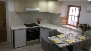 Une cuisine compacte équipée d’un four encastré, d’un lave-vaisselle et d’un coin repas avec une table dressée pour quatre personnes.