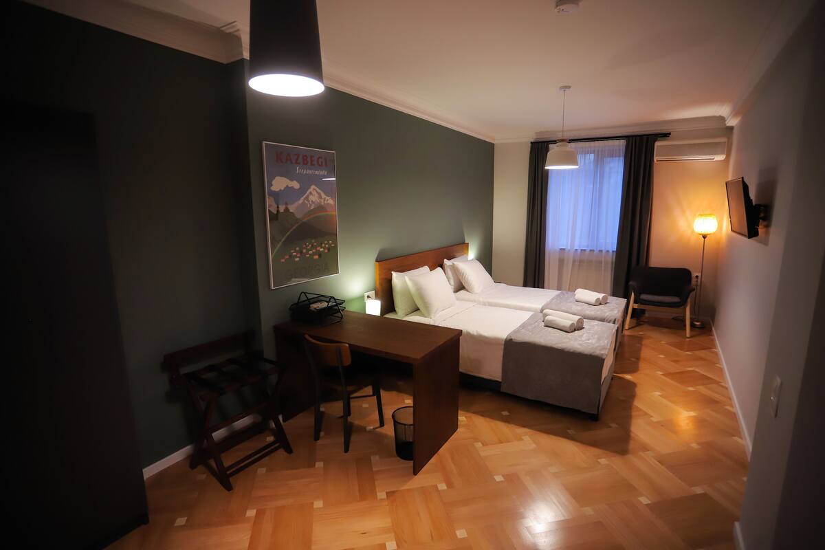 Una habitación de hotel con cama, escritorio, silla y un cartel en la pared.