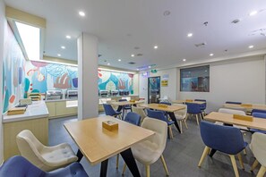 A modern dining area with tables and chairs, a buffet counter, and a colorful mural on the wall. - Hanting Hotel Shanghai Railway Station (Shanghai)