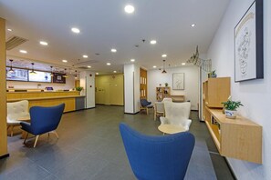 A modern reception area with a counter, seating, and a wall-mounted artwork. - Hanting Hotel Shanghai Railway Station (Shanghai)