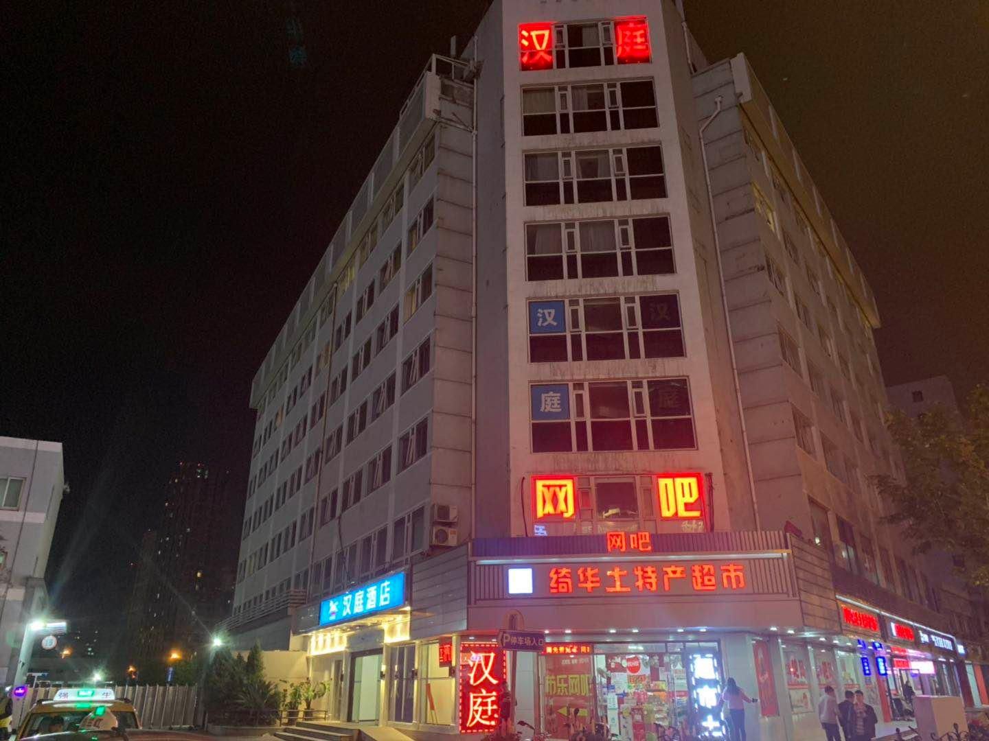A multi-story building with illuminated signage, a visible entrance, and a storefront with glass windows.