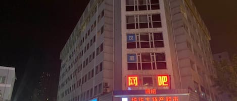 A multi-story building with illuminated signage, a visible entrance, and a storefront with glass windows.