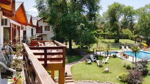 A hotel with a pool area, outdoor seating, and a well-maintained garden. - Shemak Posada (Villa General Belgrano)