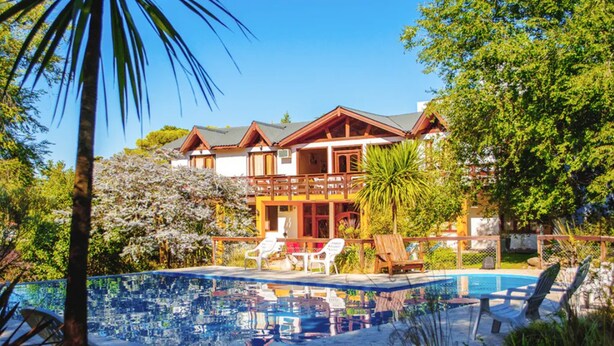 A resort with a swimming pool, lounge chairs, and a large building with multiple balconies. - Shemak Posada (Villa General Belgrano)