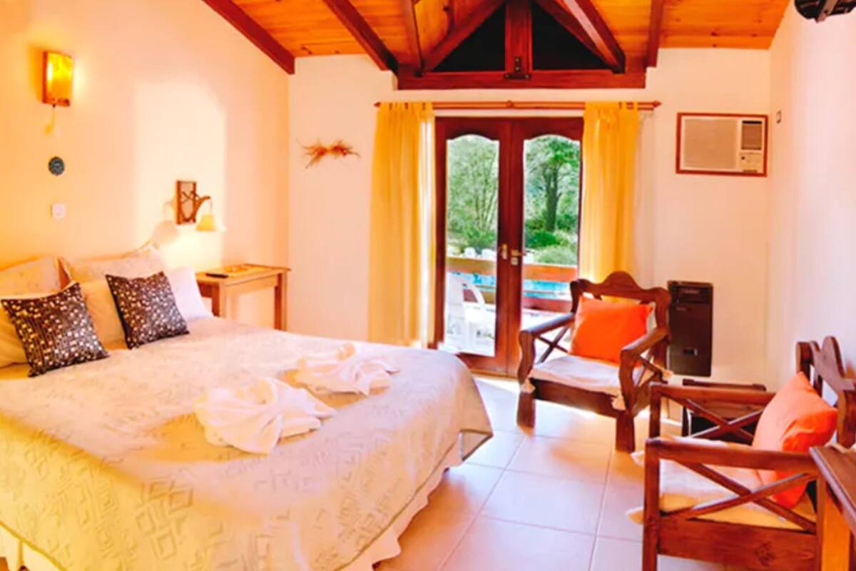 A bedroom with a bed, a desk, a chair, and a window with curtains.